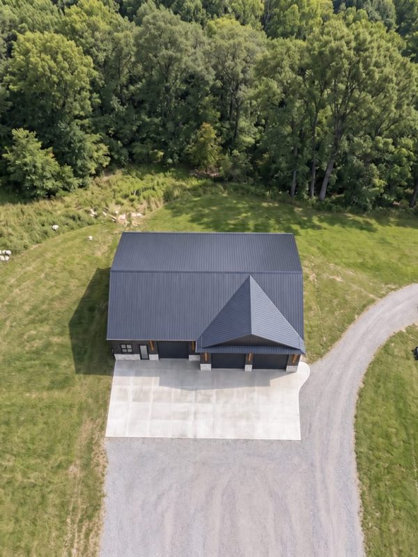 Aerial view of a custom barndominium on a wooded Northeast Ohio lot